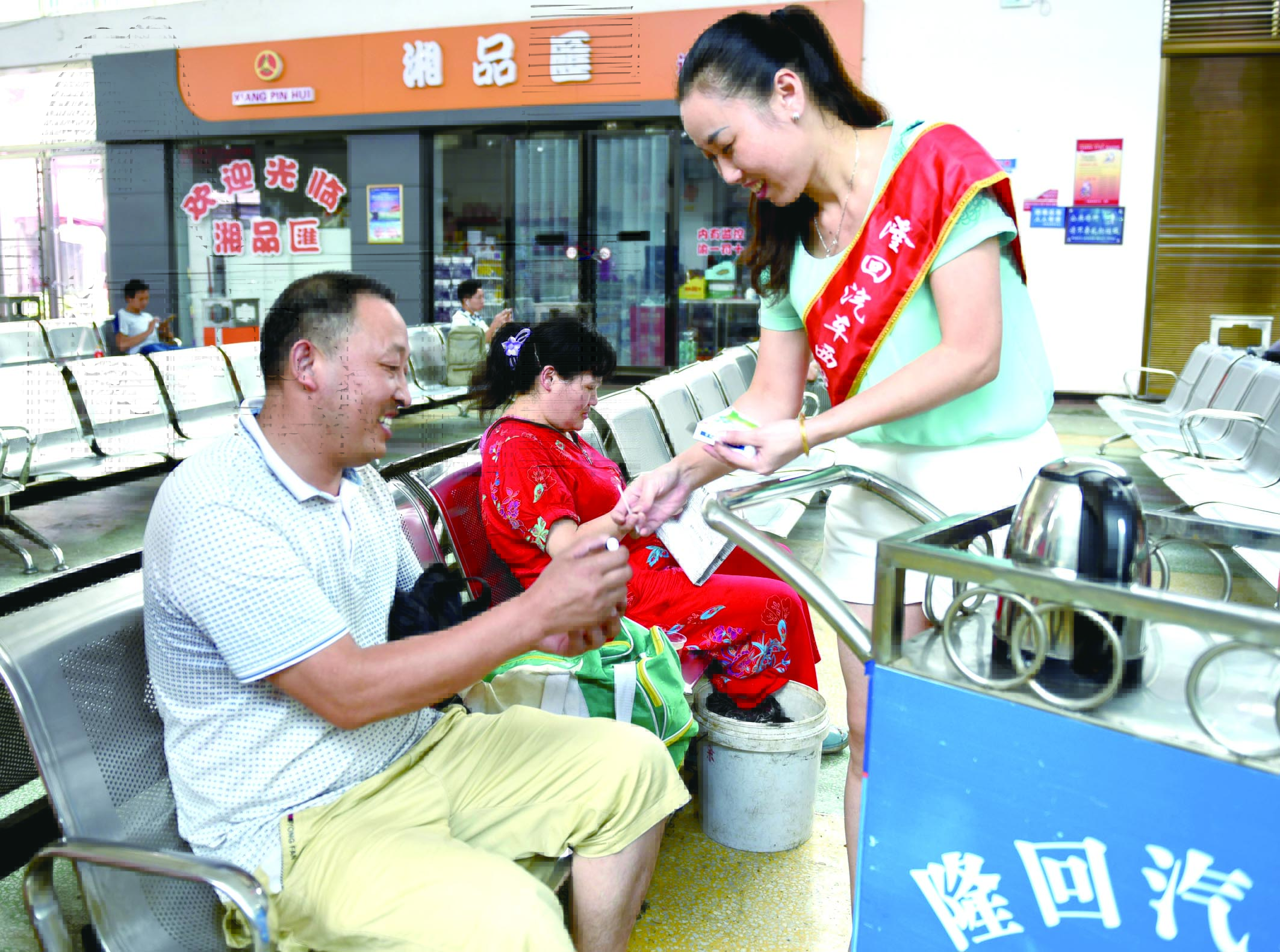 隆回分公司汽車西站工作人員正在為旅客免費(fèi)贈(zèng)送藿香正氣水。